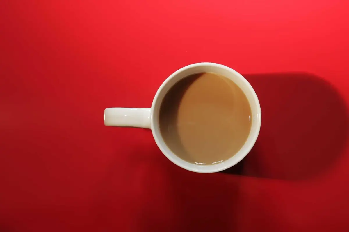 A cup of coffee from above, on red
